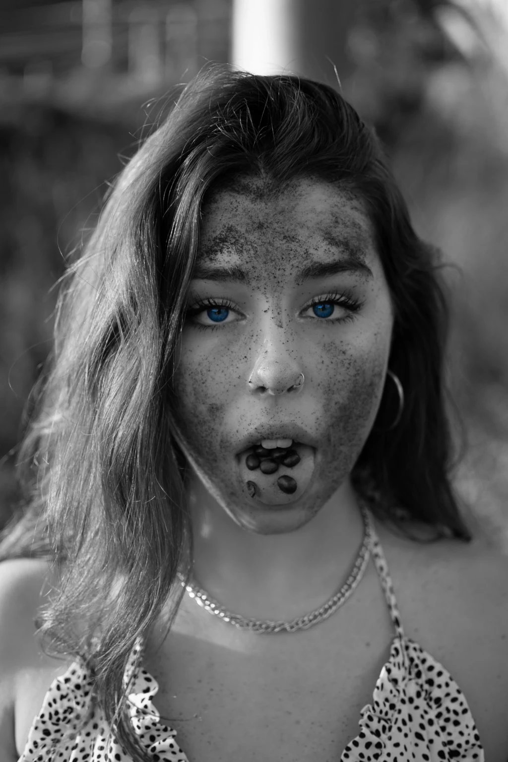 Retrato creativo en blanco y negro con ojos azules y granos de café en la lengua
