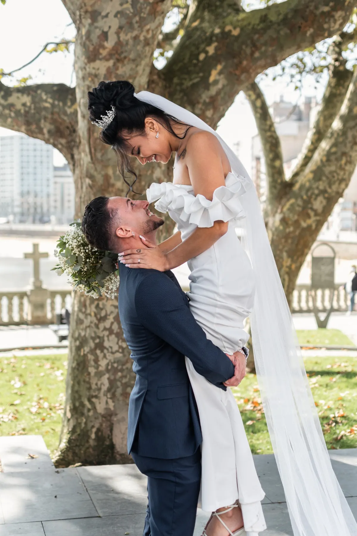 Novio levantando a la novia bajo un árbol